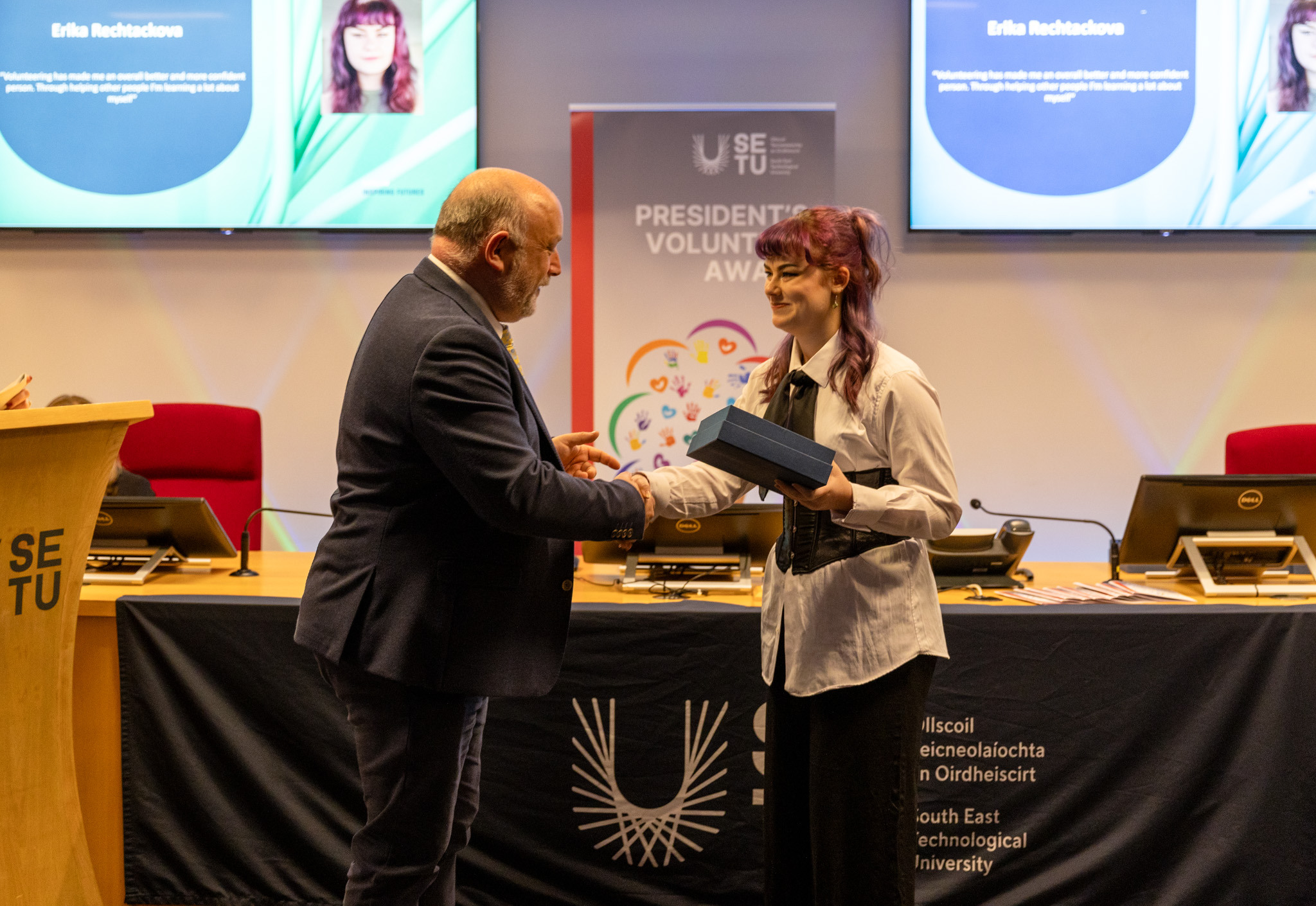 Two individuals shaking hands, one with a President’s Volunteer Awards